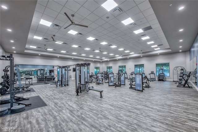 workout area featuring baseboards, visible vents, wood finished floors, a paneled ceiling, and a high ceiling