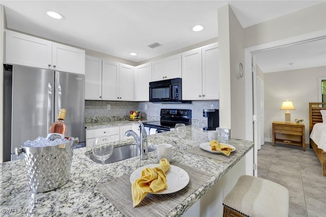 655 8th Ave S Unit 6, Naples, FL 34102 - kitchen with black appliances, light stone countertops, white cabinets, decorative backsplash, and a sink