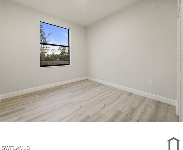 spare room featuring baseboards and wood finished floors