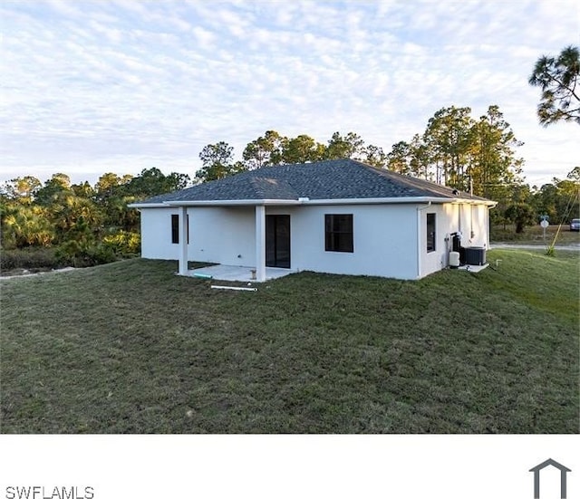 back of property featuring cooling unit, stucco siding, and a lawn