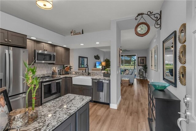350 Newport Dr Unit 1902, Naples, FL 34114 - kitchen with stainless steel appliances, a sink, light wood finished floors, decorative backsplash, and light stone counters