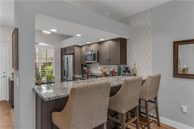 350 Newport Dr Unit 1902, Naples, FL 34114 - kitchen featuring appliances with stainless steel finishes, wallpapered walls, light wood-style floors, baseboards, and a breakfast bar