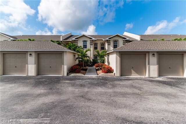 350 Newport Dr Unit 1902, Naples, FL 34114 - view of front of house featuring community garages, stucco siding, and a shingled roof