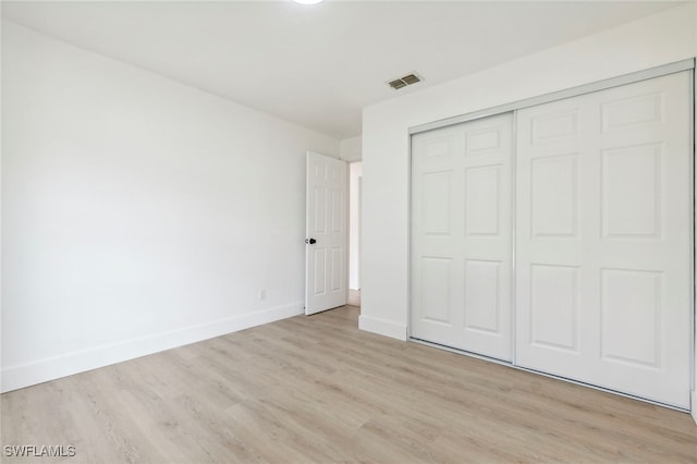 unfurnished bedroom featuring light wood-style flooring, baseboards, a closet, and visible vents