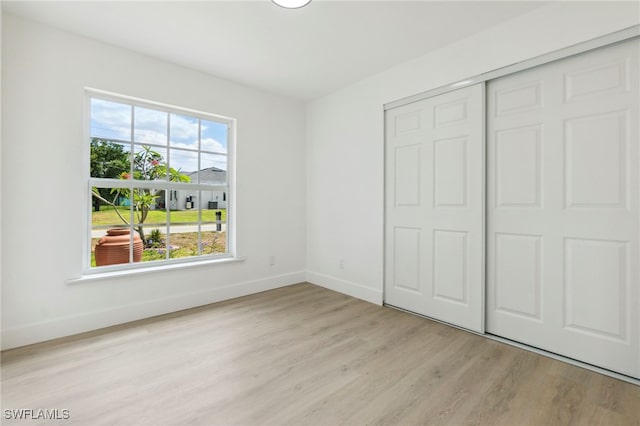unfurnished bedroom with baseboards, a closet, and wood finished floors