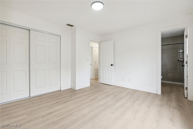 unfurnished bedroom with a closet, baseboards, visible vents, and wood finished floors