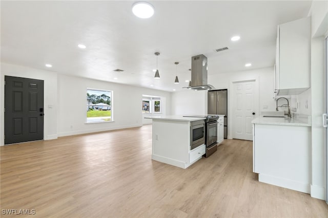kitchen with island exhaust hood, a sink, visible vents, electric stove, and light countertops
