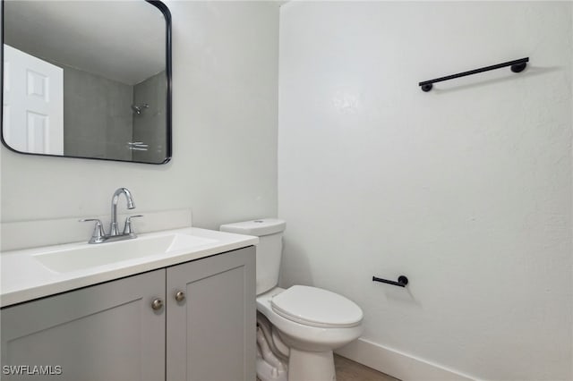 bathroom featuring toilet, baseboards, and vanity