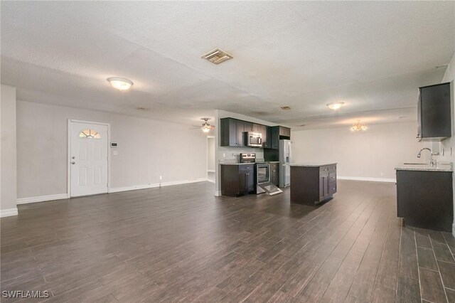 2414 Parkview Dr, Fort Myers, FL 33905 - unfurnished living room featuring dark wood-type flooring, baseboards, a sink, a ceiling fan, and a chandelier