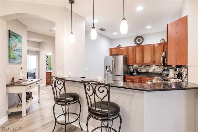 17084 Acapulco Rd Unit 222, Punta Gorda, FL 33955 - kitchen featuring stainless steel appliances, arched walkways, brown cabinets, tasteful backsplash, and a peninsula