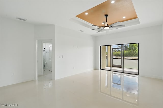 empty room featuring a tray ceiling, recessed lighting, ceiling fan, baseboards, and light tile patterned flooring