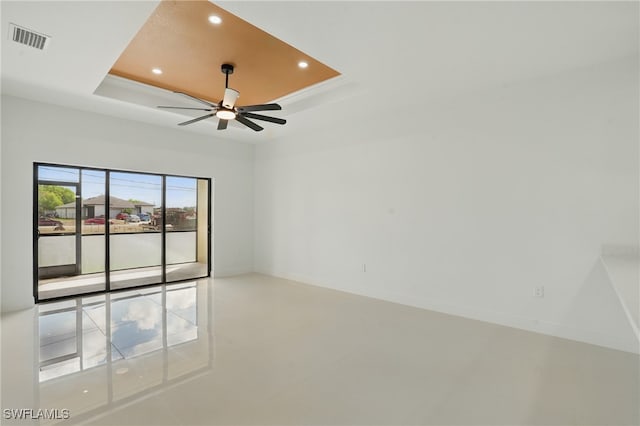 spare room with a tray ceiling, recessed lighting, a ceiling fan, and baseboards