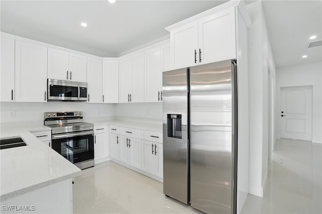 kitchen featuring stainless steel appliances, recessed lighting, light stone countertops, white cabinets, and a sink