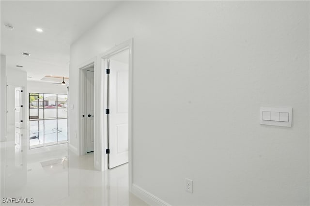 hall featuring baseboards, light tile patterned floors, and recessed lighting