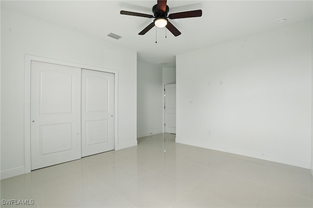 unfurnished bedroom with a closet, light tile patterned flooring, baseboards, and a ceiling fan