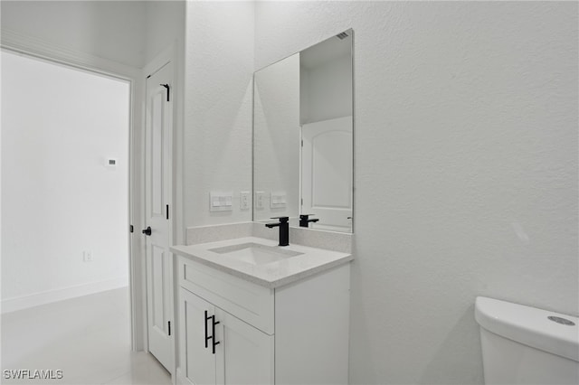 bathroom featuring vanity, toilet, and a textured wall