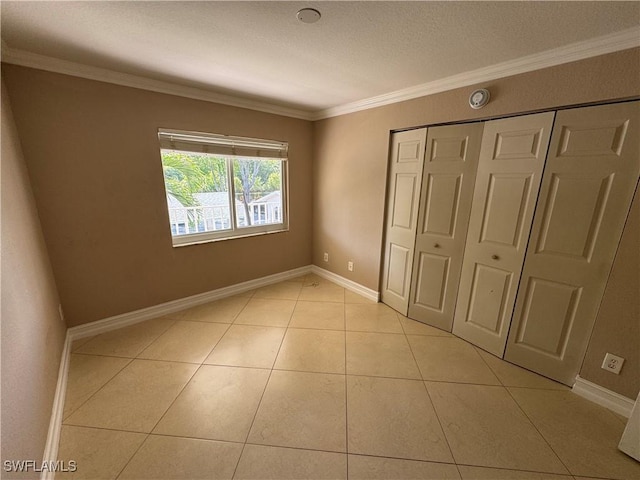 388 Belina Dr Unit 6, Naples, FL 34104 - unfurnished bedroom with a closet, a textured ceiling, baseboards, light tile patterned flooring, and crown molding