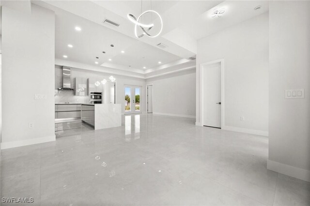 3631 68th Ave NE, Naples, FL 34120 - unfurnished living room featuring a notable chandelier, a tray ceiling, recessed lighting, baseboards, and visible vents