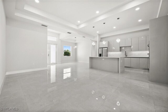 3631 68th Ave NE, Naples, FL 34120 - unfurnished living room featuring a tray ceiling, a sink, baseboards, and recessed lighting