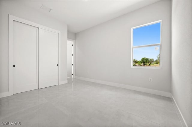 3631 68th Ave NE, Naples, FL 34120 - unfurnished bedroom with concrete flooring, a closet, and baseboards
