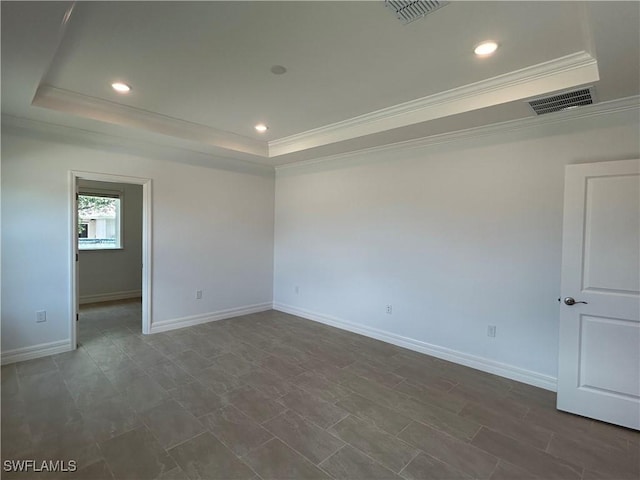 empty room with ornamental molding, a tray ceiling, and visible vents