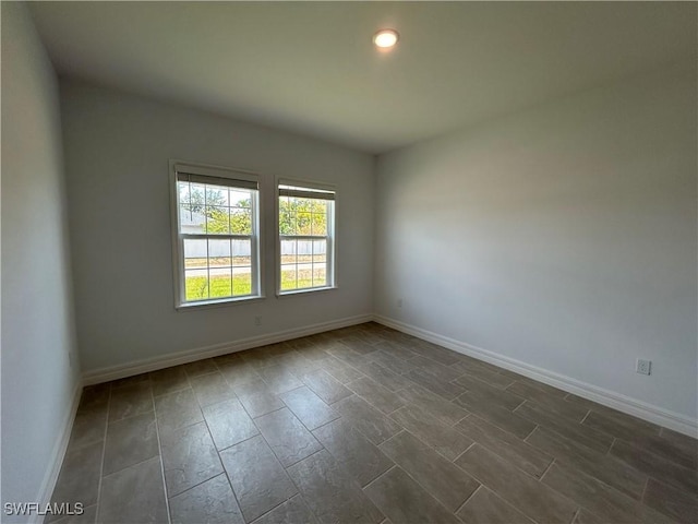 empty room featuring baseboards and recessed lighting