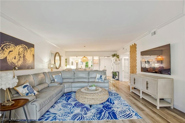 living room with light wood-style flooring and ornamental molding
