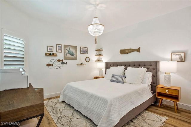 bedroom with a chandelier, wood finished floors, and baseboards