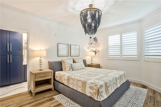 bedroom featuring crown molding, light wood finished floors, and baseboards