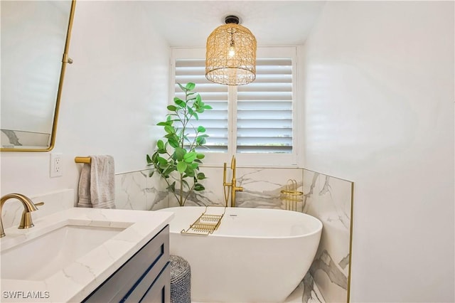 bathroom with tile walls, a soaking tub, vanity, and a wainscoted wall