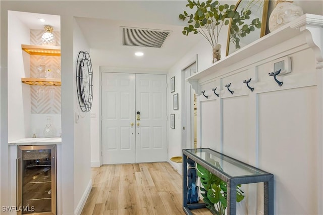mudroom with beverage cooler, light wood-style floors, baseboards, a bar, and recessed lighting