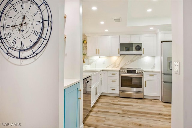 kitchen with appliances with stainless steel finishes, recessed lighting, light wood finished floors, white cabinets, and light countertops