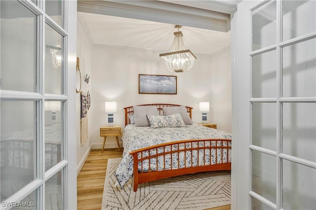 bedroom with wood finished floors, a chandelier, and baseboards