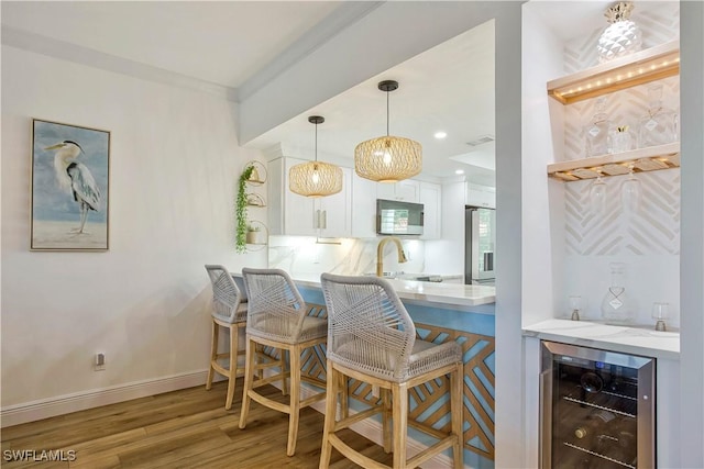 indoor dry bar featuring beverage cooler, wood finished floors, decorative light fixtures, refrigerator with ice dispenser, and crown molding