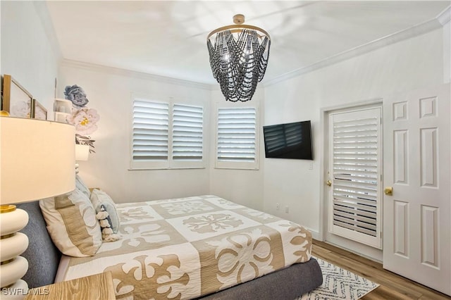 bedroom featuring a chandelier, crown molding, and wood finished floors