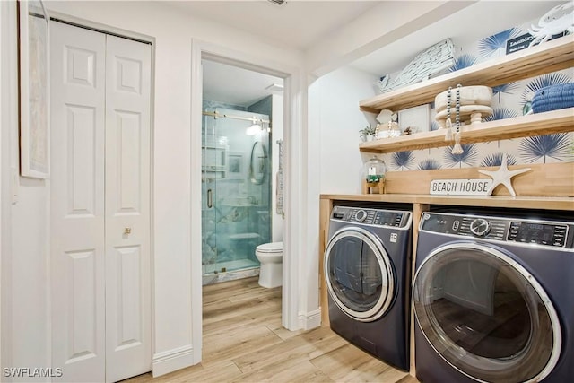 clothes washing area featuring washing machine and dryer and light wood finished floors