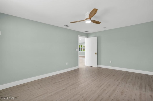 spare room featuring baseboards, visible vents, a ceiling fan, and wood finished floors
