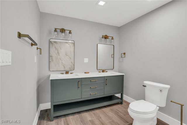 bathroom with baseboards, toilet, a sink, and wood finished floors