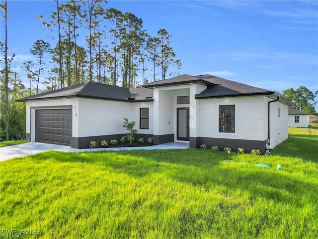 prairie-style house featuring concrete driveway, an attached garage, stucco siding, and a front lawn