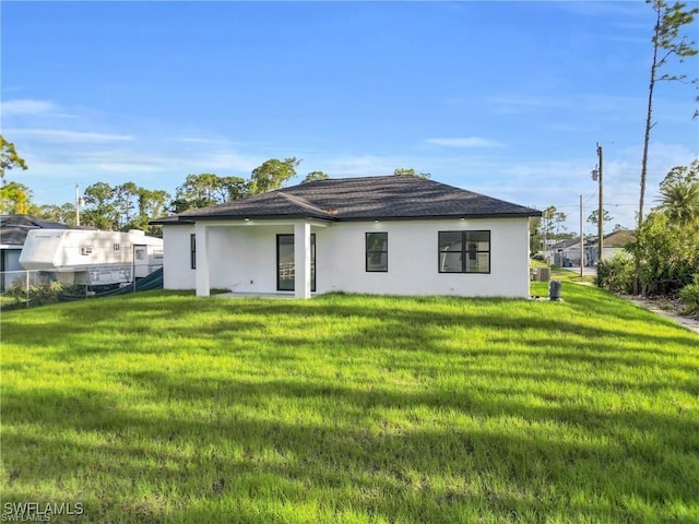 back of house featuring fence, stucco siding, and a lawn