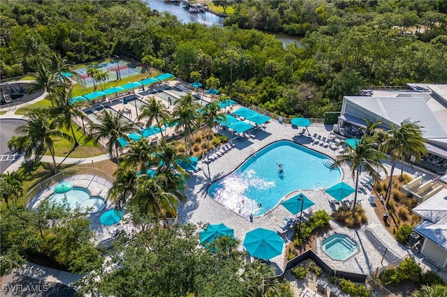 drone / aerial view of a pool area and a heavily wooded area
