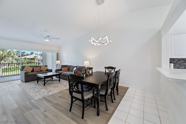 dining area with ceiling fan, a chandelier, lofted ceiling, and light wood finished floors
