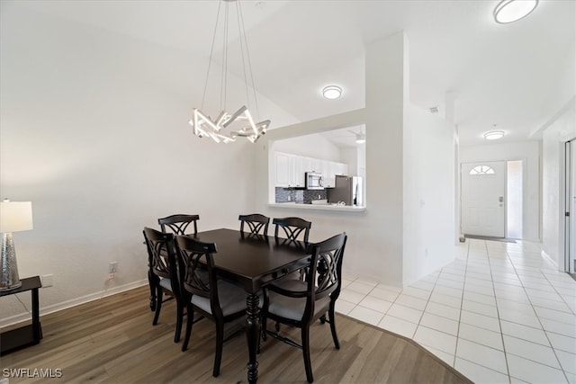 dining space with a chandelier, light wood-style floors, and baseboards