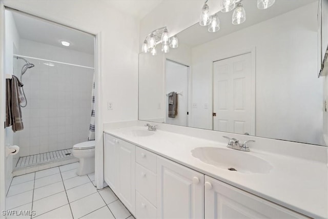bathroom featuring tile patterned flooring, toilet, double vanity, and tiled shower