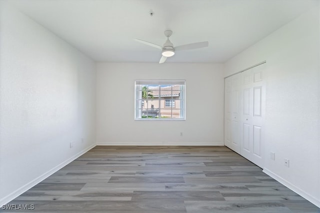 unfurnished bedroom with wood finished floors, baseboards, and a closet