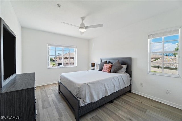 bedroom with light wood-style floors, baseboards, and a ceiling fan