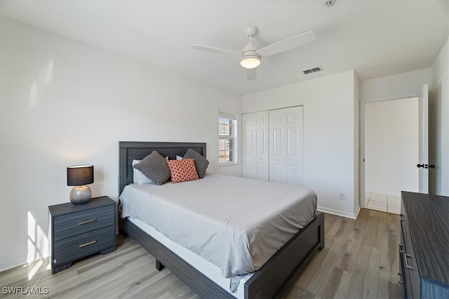 bedroom with light wood-type flooring, a closet, a ceiling fan, and baseboards
