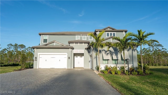 view of front of house with an attached garage, decorative driveway, stucco siding, and a front lawn