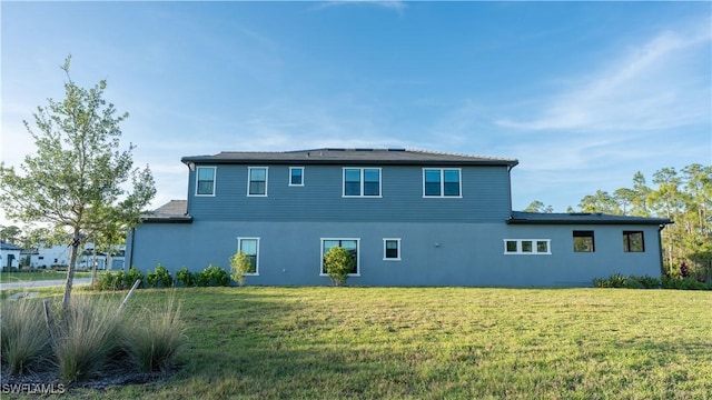 rear view of property featuring a yard and stucco siding