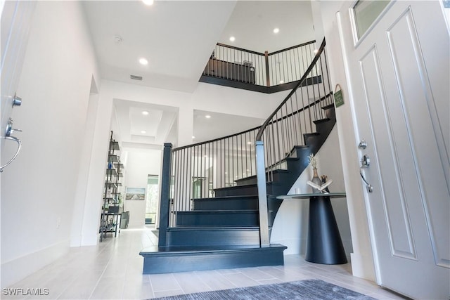 stairs with recessed lighting, visible vents, and a towering ceiling